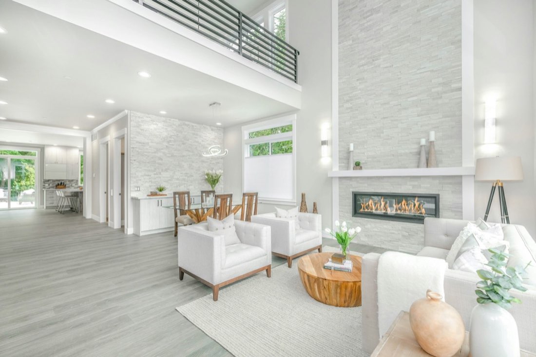 HDR real estate photo of a bright open-plan living room with a linear fireplace and large windows.