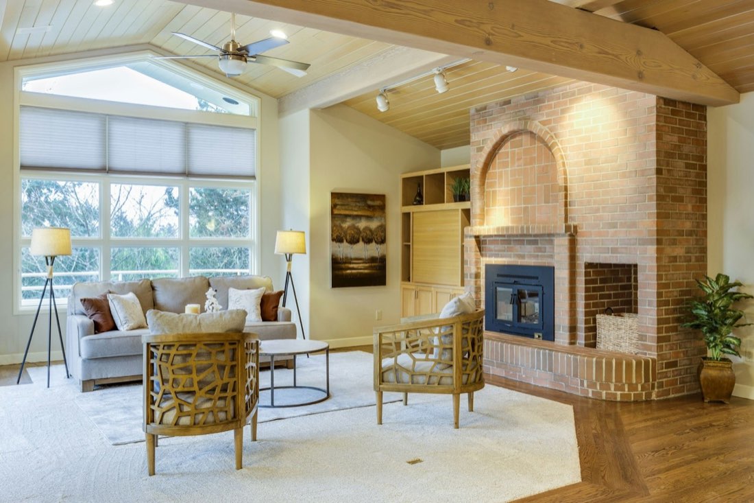 Real estate photo of a living room with a vaulted wood-panelled ceiling and abundant natural light.