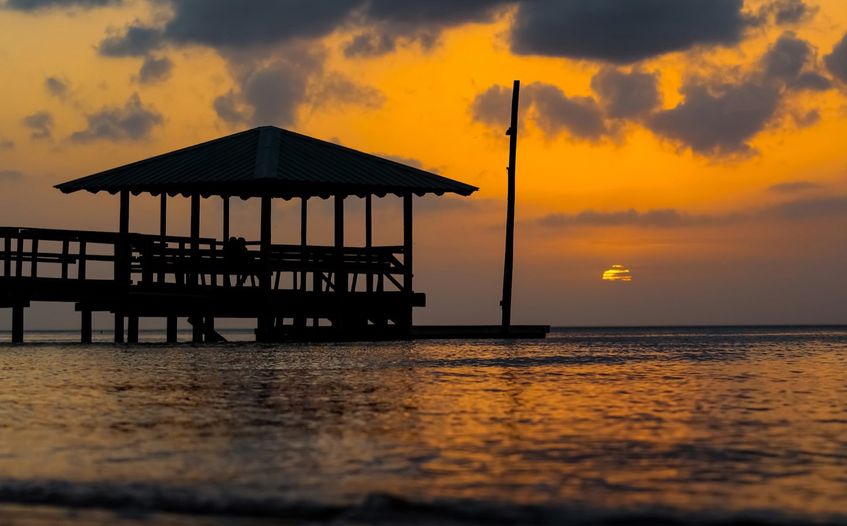 A genuine dusk photograph over the water — deep gold light, real shadows and reflections.